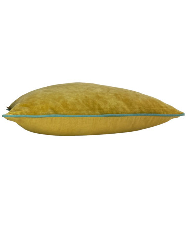 Vue de profil du coussin en velours ocre montrant le rembourrage généreux et le passepoil contrasté bleu.