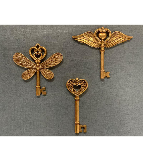 Trio de clés murales décoratives dorées de différentes tailles en résine, incluant la clé ailes cœur et la clé papillon.