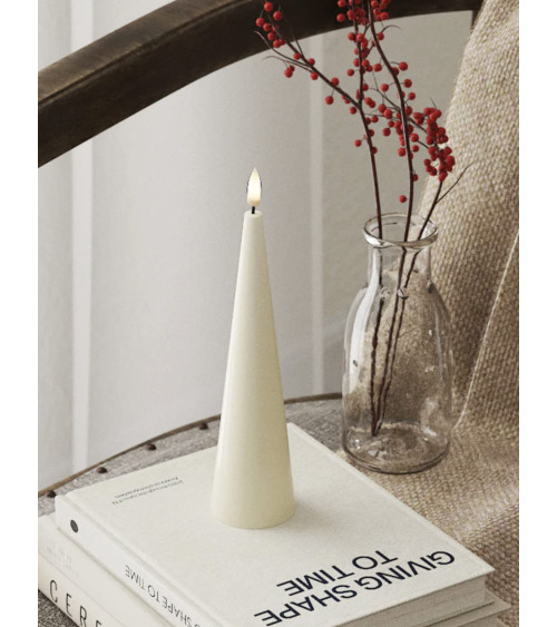 Bougie conique LED ivoire 5x20 cm posée sur un livre dans une décoration minimaliste et chaleureuse