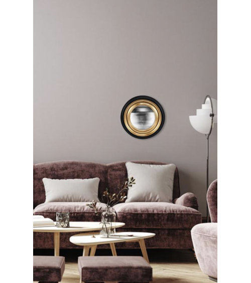 Miroir convexe noir et doré accroché dans un salon moderne