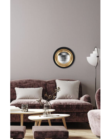Miroir convexe noir et doré accroché dans un salon moderne