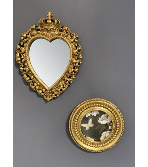 Miroir baroque doré en forme de cœur accroché sur un mur gris, accompagné d’un cadre rond décoratif