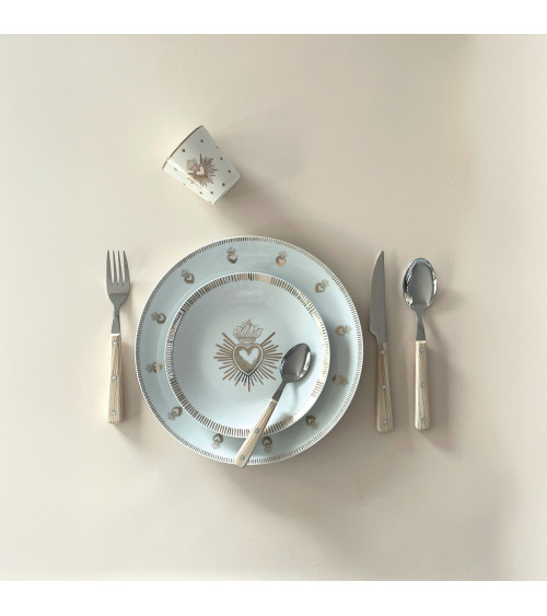 Assiette Ex-Voto dorée présentée sur une table dressée avec couverts assortis