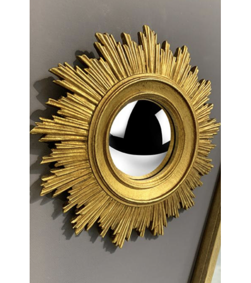 Détail gros plan miroir oeil de sorcière convexe doré, décoration murale.