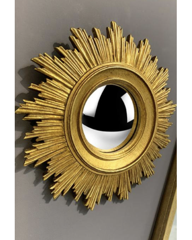 Détail gros plan miroir oeil de sorcière convexe doré, décoration murale.