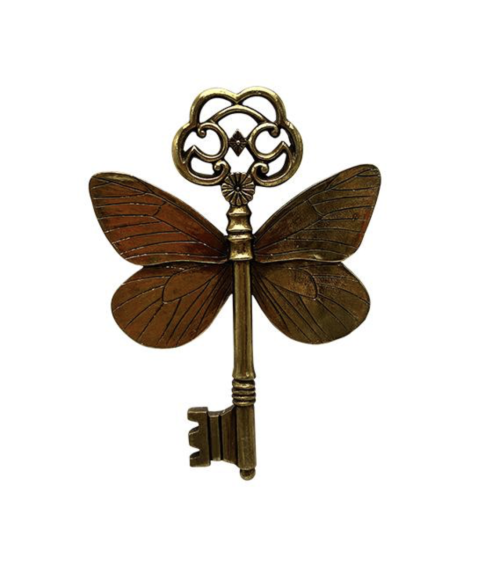 Décoration murale en forme de clé ancienne avec ailes de papillon dorées, style vintage et fantastique.