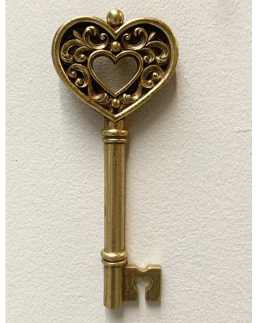 Décoration murale originale : clé ancienne dorée avec pommeau en forme de cœur travaillé et détails baroques.