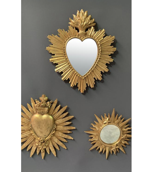Trio de décorations murales dorées incluant un miroir cœur soleil, un ex-voto cœur enflammé et un miroir étoile.