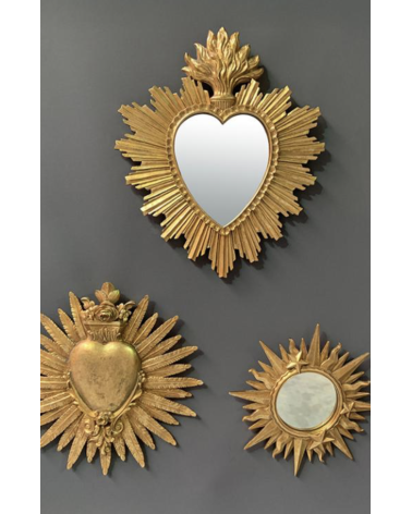 Trio de décorations murales dorées incluant un miroir cœur soleil, un ex-voto cœur enflammé et un miroir étoile.