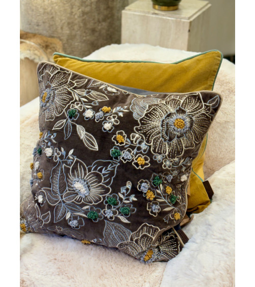 Ambiance cocooning avec un grand coussin gris anthracite brodé posé sur un plaid en fourrure blanche.