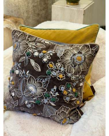 Ambiance cocooning avec un grand coussin gris anthracite brodé posé sur un plaid en fourrure blanche.