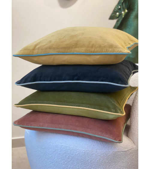 Pile de housses de coussins en velours colorés : terracotta, vert forêt, bleu nuit et ocre.