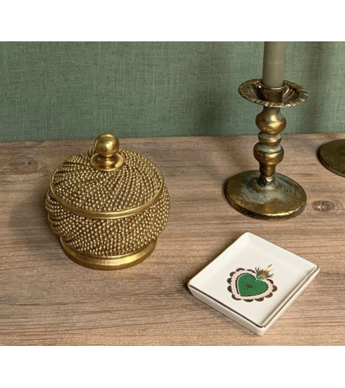 Décoration de table avec boîte perlée dorée, bougeoir ancien et vide-poche sur un meuble en bois.