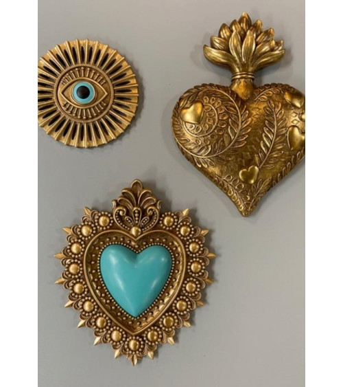 Composition murale de trois ex-voto dorés : cœur bleu, œil protecteur et grand cœur sacré.