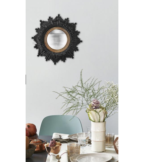 Miroir de sorcière convexe style soleil accroché au mur au-dessus d'une table de salle à manger élégante