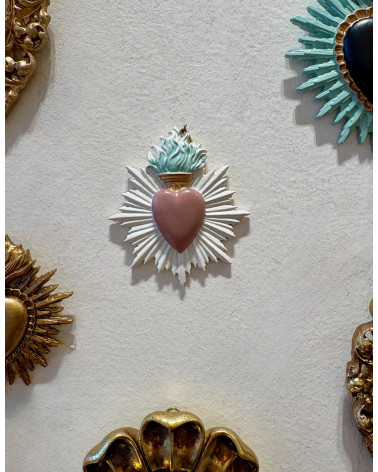 Accumulation d'ex-votos et cœurs sacrés sur un mur blanc pour une décoration de style cabinet de curiosités.