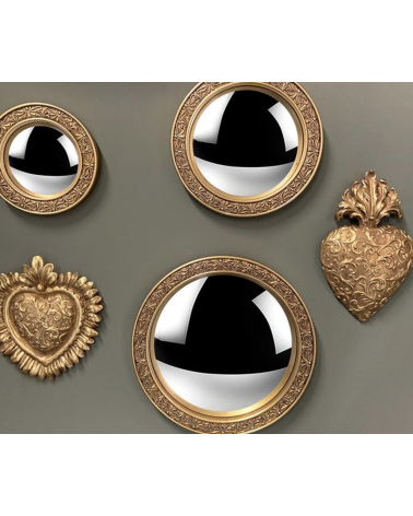 Ex-voto cœur doré exposé sur un mur avec des miroirs ronds pour une décoration murale style baroque