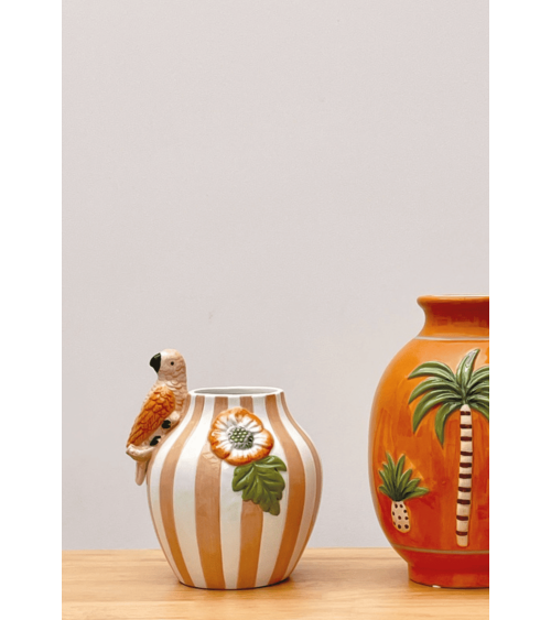 Vase décoratif en faïence rose avec oiseau posé sur une table