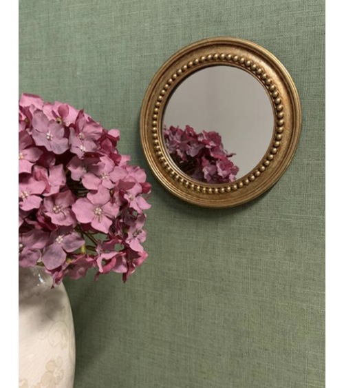 Petit miroir mural rond doré dans une décoration élégante et romantique