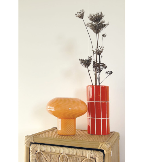 Vase en céramique orange effet carrelage avec fleurs séchées sur meuble en rotin