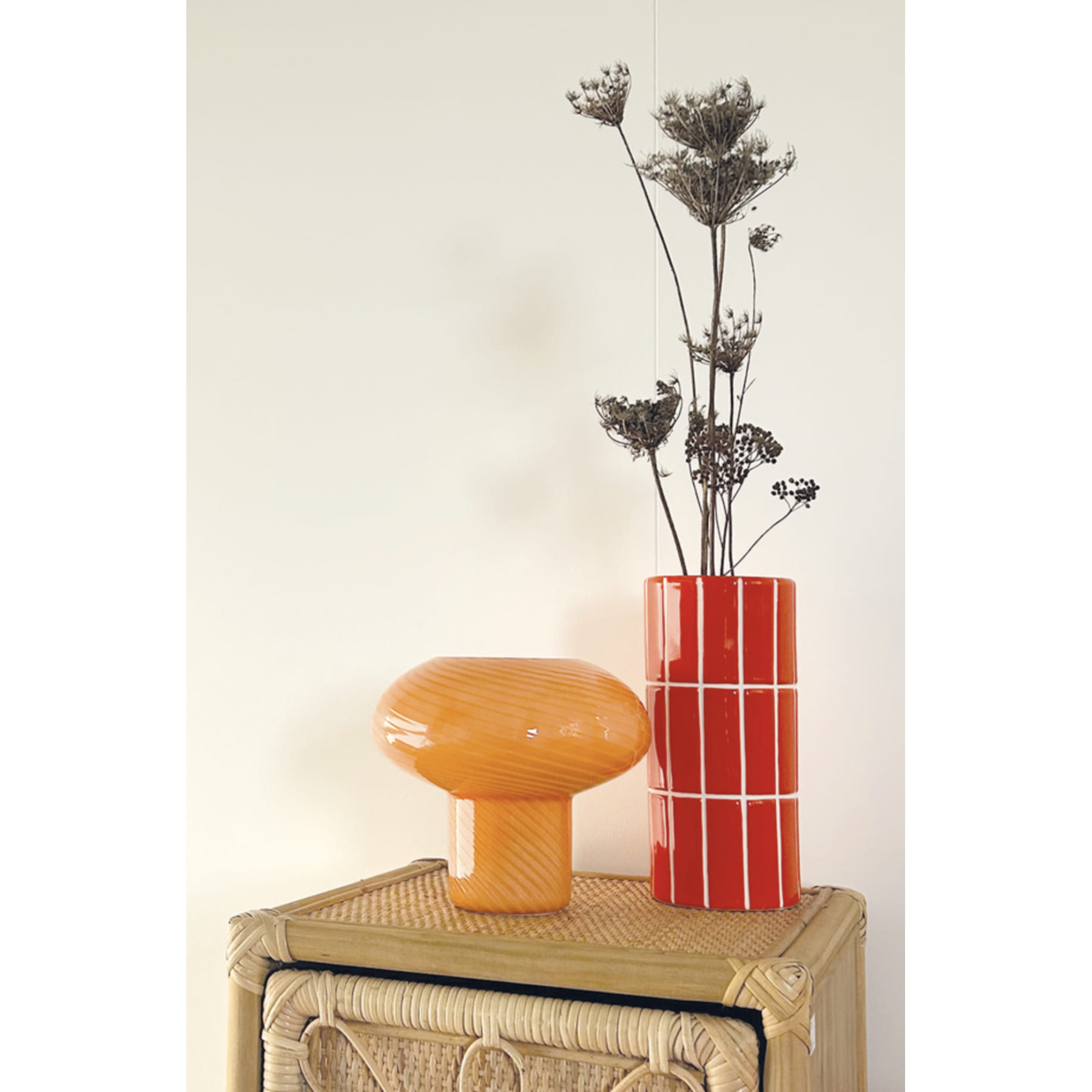Vase en céramique orange effet carrelage avec fleurs séchées sur meuble en rotin