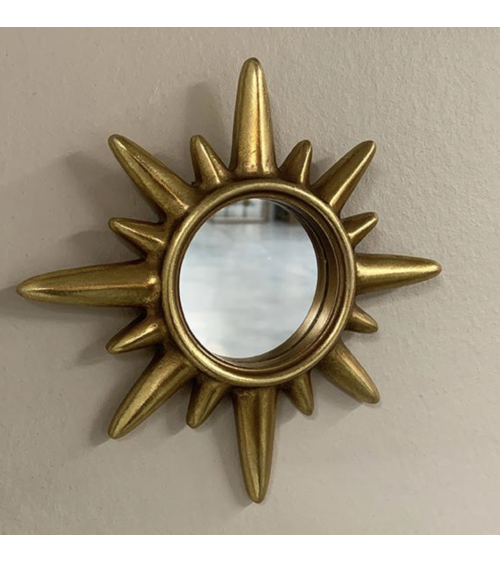 Miroir soleil doré installé sur un mur dans une décoration élégante