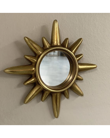 Miroir soleil doré installé sur un mur dans une décoration élégante